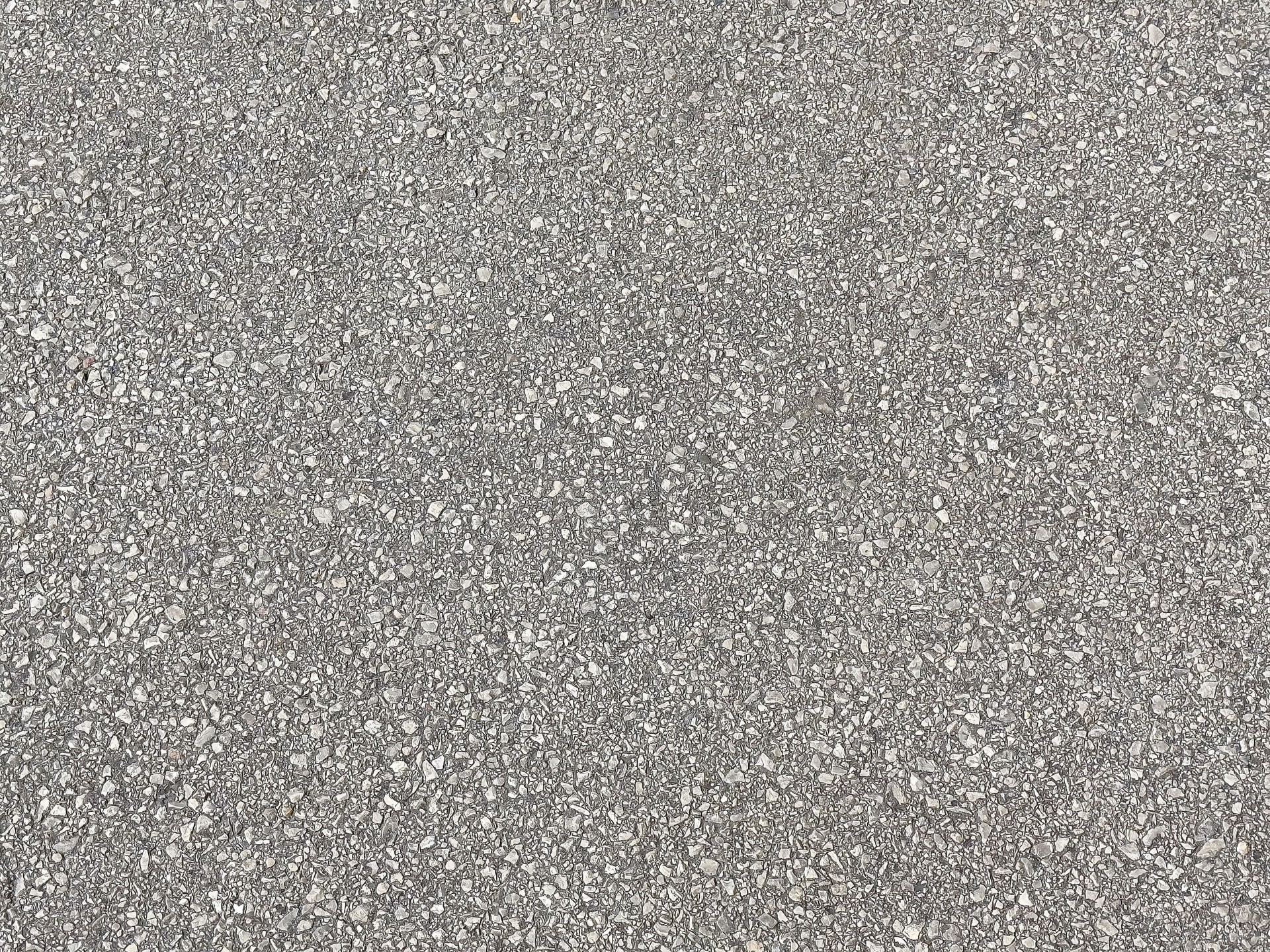 Close-up of rough textured gray asphalt surface with pebbles